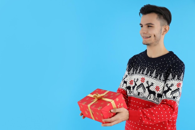 Gars attrayant avec un cadeau de Noël sur fond bleu