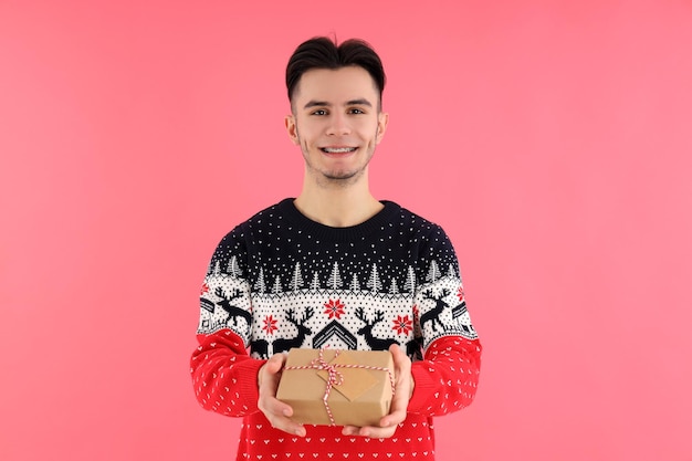 Gars attrayant avec un cadeau de Noël sur fond rose