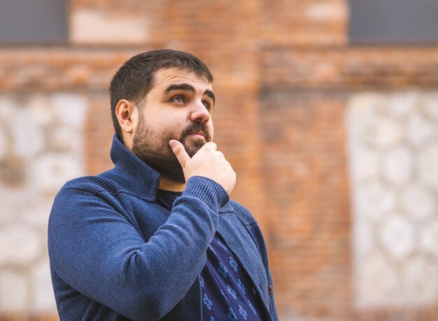 Gars barbu en pull bleu réfléchie à la recherche dans la rue