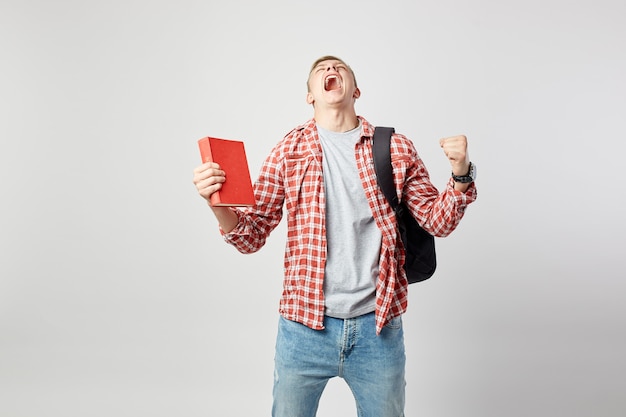 un gars blond joyeux tient un livre dans sa main et crie