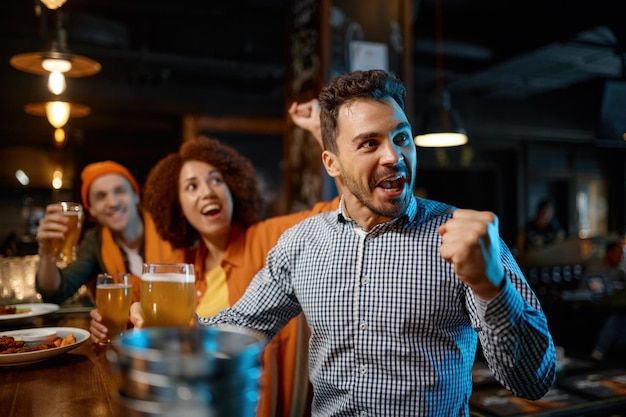 Les gars boivent de la bière artisanale et regardent un match de football. Divers groupes de jeunes se reposent dans un bar sportif