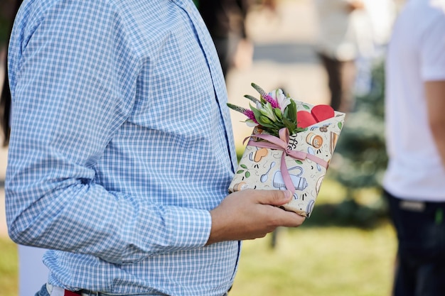 Un gars dans une chemise élégante tient un cadeau dans une boîte