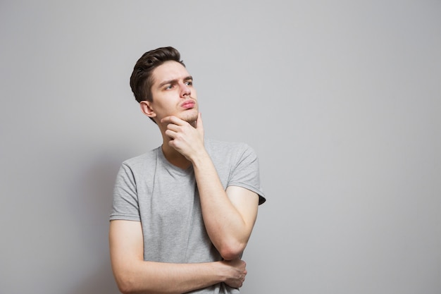 Un gars dans un T-shirt gris avec des émotions sur son visage.