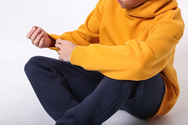 Un gars dans un vêtement de sport élégant et confortable sur fond clair, prise de vue en studio pour un magazine, détails de tissus et de fleurs