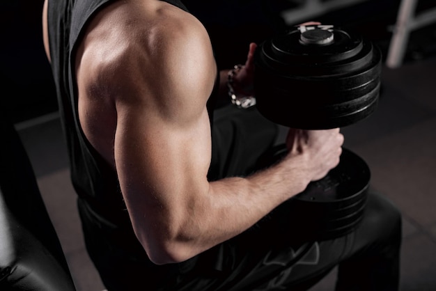 Le gars est engagé dans la salle de gym avec des haltères le concept de vie sportive