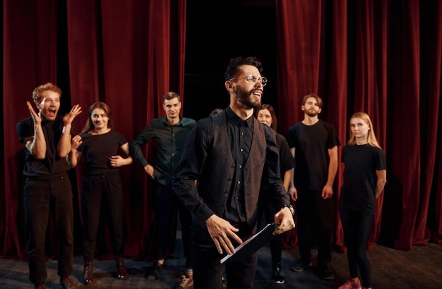 Gars expressif pratiquant son rôle Groupe d'acteurs vêtus de vêtements de couleur sombre en répétition au théâtre