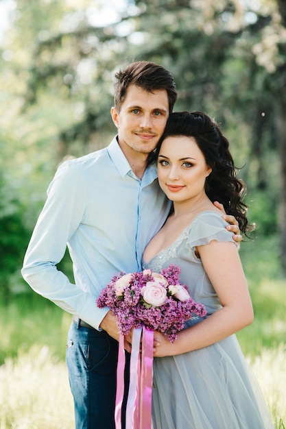 Un gars et une femme marchent dans le jardin printanier des lilas avant la cérémonie de mariage