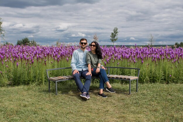 Un gars et une fille amoureuse sont assis sur un banc dans le parc près de fleurs