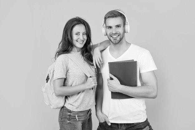 Un gars et une fille de la journée de la connaissance tiennent des étudiants universitaires sur un ordinateur portable sur fond jaune