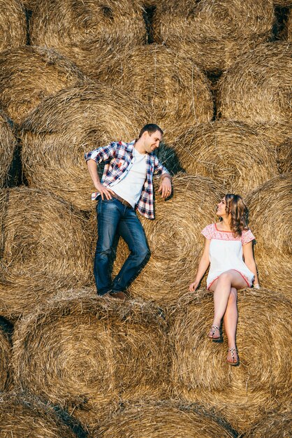 Un gars avec une fille lors d'une promenade estivale dans le champ près de meules de foin rondes