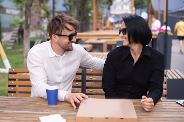 Un gars et une fille ont une boîte à pizza à une table dans la rue