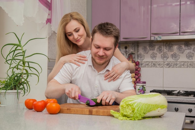 Le gars et la fille préparent une salade dans la cuisine