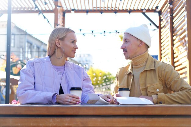 Un gars et une fille s'assoient sur une terrasse d'été par temps ensoleillé et se regardent amoureux