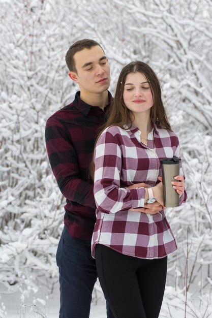 Le gars et la fille se reposent dans les bois d'hiver Mari et femme dans la neige Jeune couple