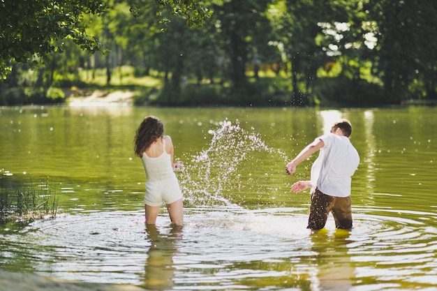 Un gars et une fille vaporisent de l'eau dans l'étang à la nature 6308