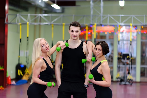 Le gars avec les filles posant dans la salle de gym