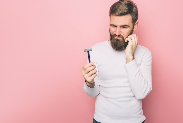 Un gars frustré tient un rasoir et ne sait pas quoi en faire