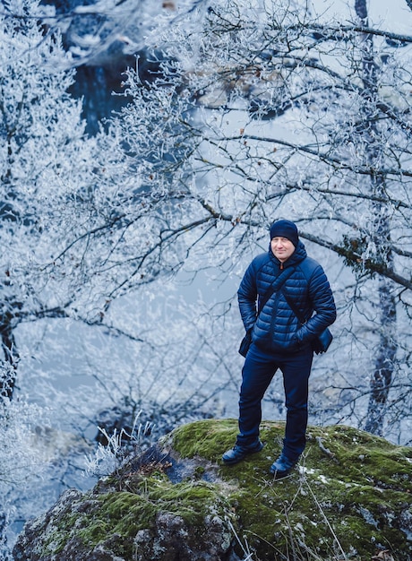 Un gars heureux avec un appareil photo debout dans la forêt. Photographe masculin regardant l'appareil photo tout en se préparant à prendre des photos en plein air. Angle élevé