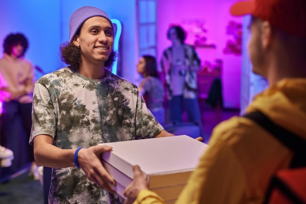 Un gars heureux regardant le courrier et prenant une pile de boîtes avec une pizza commandée