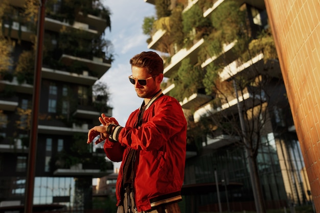 Les gars hipster portent des vêtements cool marchant dans la rue en regardant la montre, pendant la journée, les espaces des bâtiments.