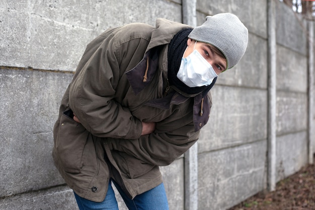 Photo un gars infecté par un coronavirus avec un masque facial médical perd connaissance. infecté par le nouveau virus mortel chinois ncov-2019.