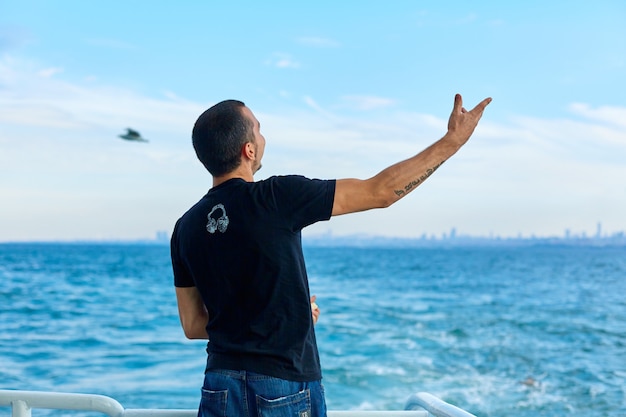 Le gars jette du pain aux mouettes qui survolent le ferry. Istanbul, Turquie - 28.07.2017