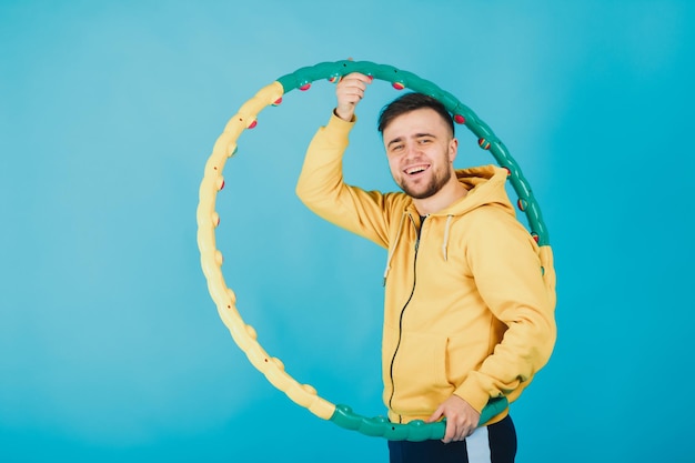 un gars joyeux dans un chemisier jaune avec un hula hoop montre un goût sur fond bleu