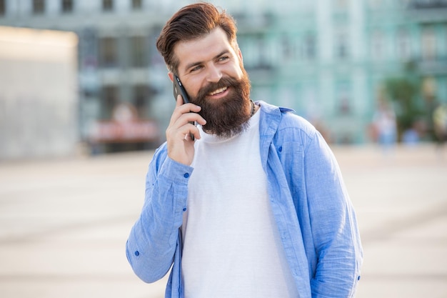 Un gars joyeux parle sur un smartphone à l'extérieur Un gars parle sur un smartphone dans la rue photo d'un gars parle sur un smartphone Un gars parle sur un smartphone à l'extérieur