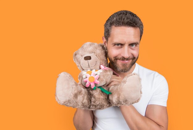 Un gars joyeux tient un ours de jouet de la Saint-Valentin dans un studio. Un gars avec un ours de jeu pour la Saint-Ventin. Une photo d'un gars tenant un ours de jeux de la saint-Valentin.