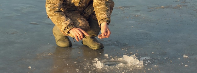 Le gars sur la pêche d'hiver au trou attrape une petite canne à pêche Gros plan d'une main avec une canne à pêche d'hiver