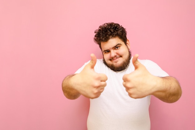 Un gars positif avec des cheveux en surpoids et bouclés montre un geste comme