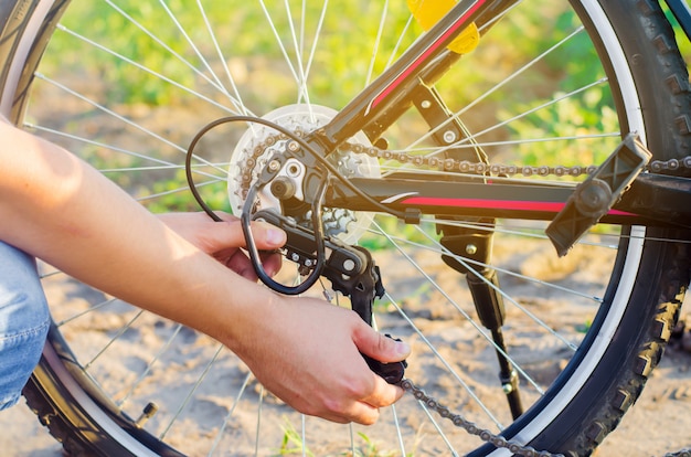 Le gars répare le vélo. réparation de la chaîne. cycliste. unratitude sur la route, voyage, gros plan.