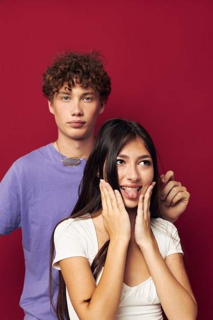 Un gars se tient derrière une fille et tient ses cheveux sur fond rouge