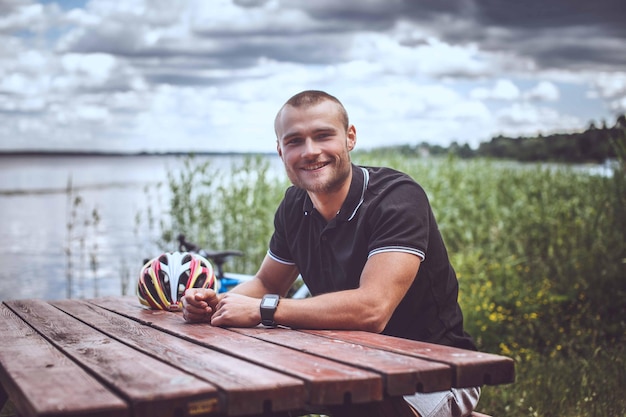 Un gars souriant à la table près du grand lac.