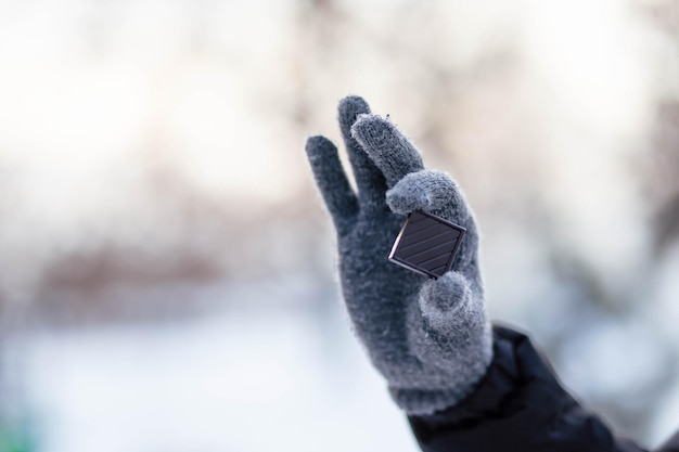 Le gars tient du chocolat dans des gants Mains dans des gants d'hiver gris Palmier avec gant dans la neige