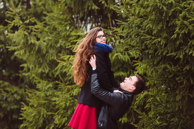 Le gars tient une fille sur des sapins