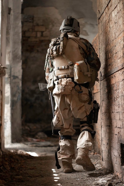 un gars en uniforme militaire américain dans une vieille allée abandonnée se déplace avec un pistolet airsoft sports gam