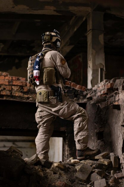 un gars en uniforme militaire américain se tient dans un bâtiment délabré sur un tas de chambres airsoft