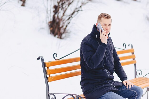 Le gars en veste d&#39;hiver parle au téléphone dans la rue