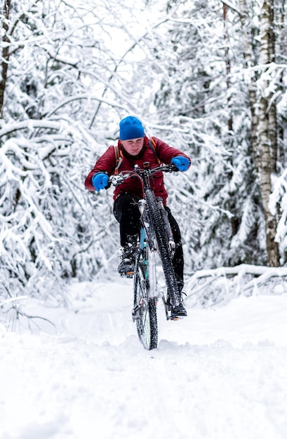 Photo un gars en veste rouge fait du vélo en hiver dans la forêt