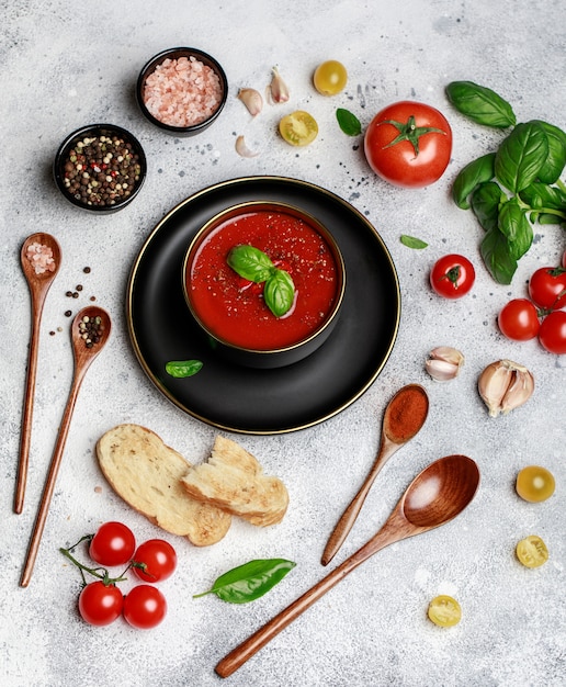 Gaspacho espagnol de soupe aux tomates froides dans un bol blanc sur un fond de pierre grise