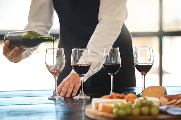 Gastronomie de luxe et hospitalité avec un serveur versant du vin rouge dans un restaurant Préparation d'une dégustation de vin avec un sommelier professionnel bon service avec une boisson de qualité par un vigneron masculin