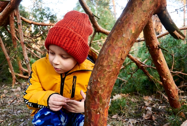 Gâte le garçon en veste et chapeau dans la forêt