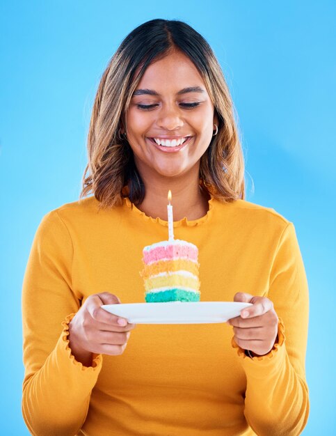 Gâteau d'anniversaire bonne fête et femme en studio fond bleu et célébration Dessert arc-en-ciel modèle féminin et bougie de bonbons d'événement spécial et sourire pour célébrer le souhait de bonheur et la surprise