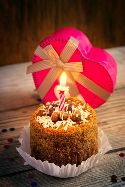 Gâteau d'anniversaire avec bougie et un cadeau sur le vieux fond en bois, teinté