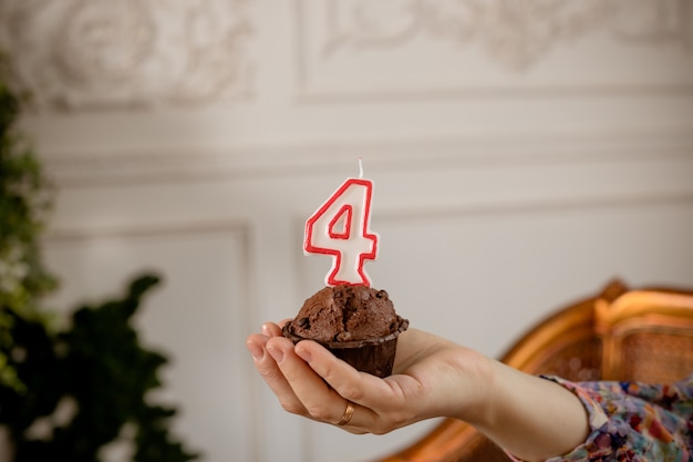 Gâteau d'anniversaire avec bougie à la main. muffin avec numéro quatre en haut, anniversaires. petits gâteaux d'anniversaire de célébration.