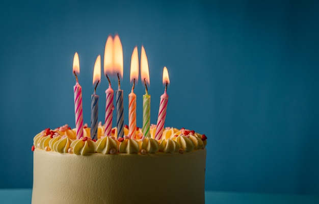 Gâteau d'anniversaire avec bougies colorées sur fond de couleur bleue