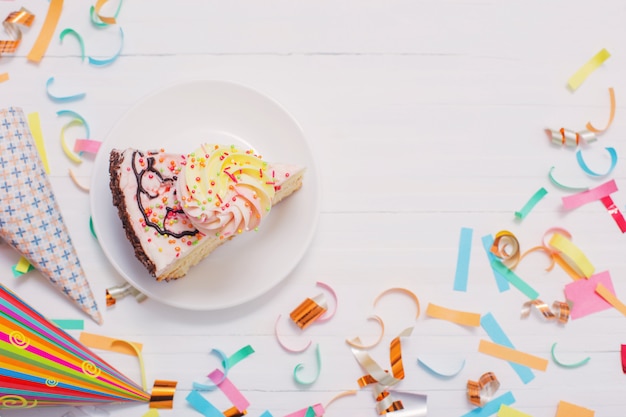 Gâteau d'anniversaire et confettis sur fond de bois blanc