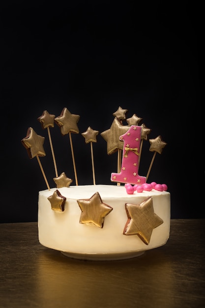 Gâteau d'anniversaire décoré du numéro 1 rose et des étoiles d'or de pain d'épice