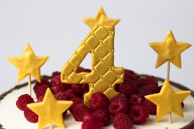 Gâteau d'anniversaire avec étoiles d'or et numéro quatre et framboises